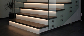 Eine Treppe mit Glasgeländer, LED-Leuchten und Produkten. Raumausstattung Merget | Goethestraße 43 | 63814 Mainaschaff